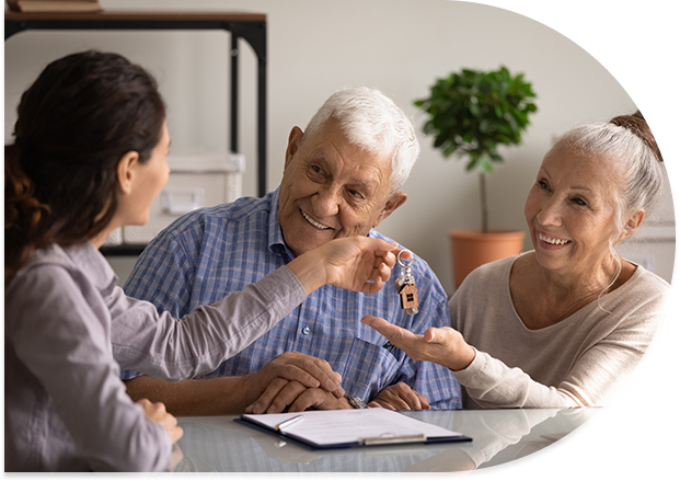 Agent handing elderly couple house keys.