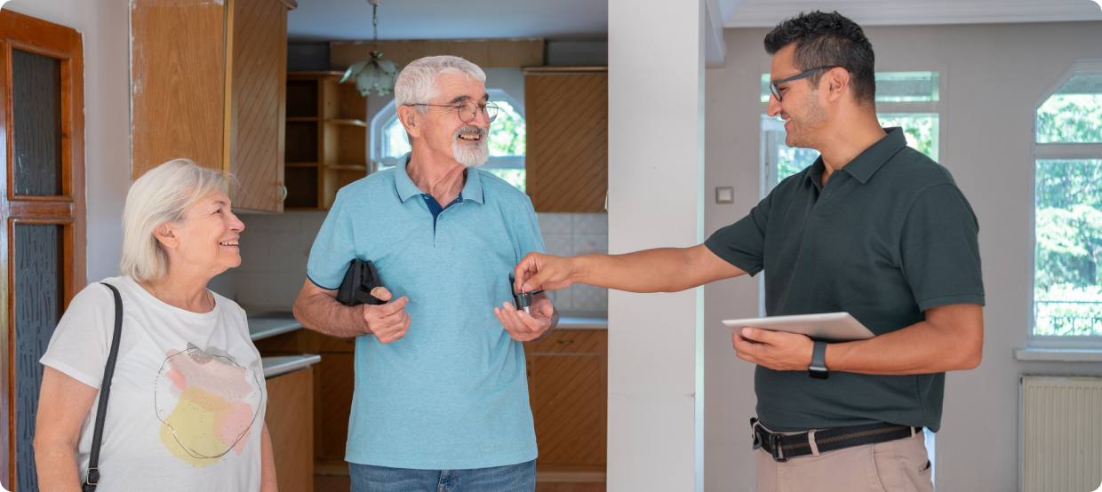 Realtor handing keys to happy senior couple.