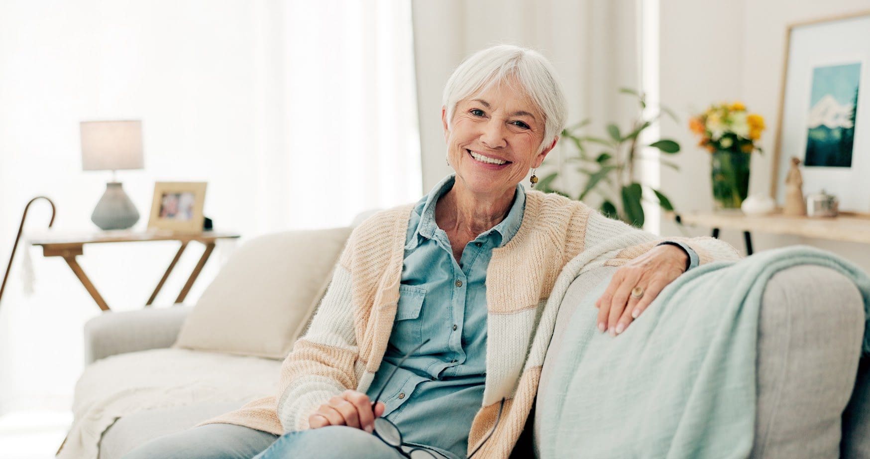 A woman sitting on top of a couch in front of a window.